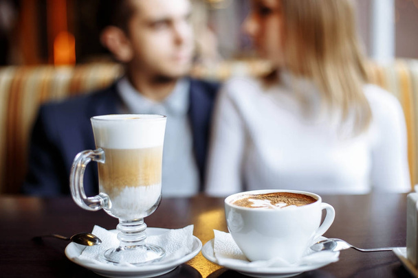 Coffee drinks on a table with a pair of lovers in the background - Foto, Imagen