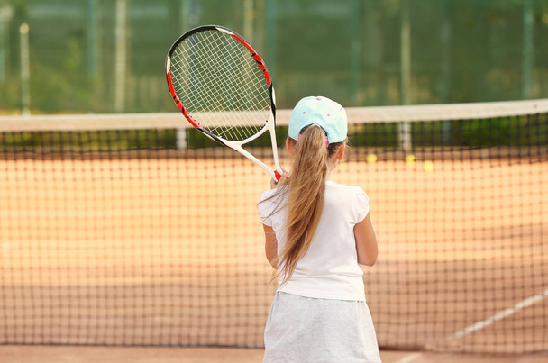 Мила дівчинка грає в теніс на корті
 - Фото, зображення