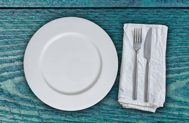 Empty plate and cutlery on petrol colored wood - Foto, immagini