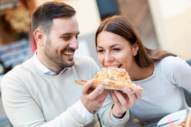 Mies syöttää tyttöystävälleen pizzaa
 - Valokuva, kuva