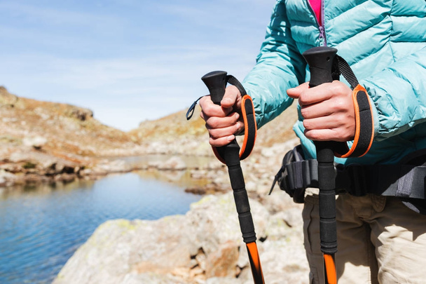Close-up of female hands with trekking sticks for Nordic walking against the background of alpine lake and distant Caucasian Rocks - Foto, Imagem