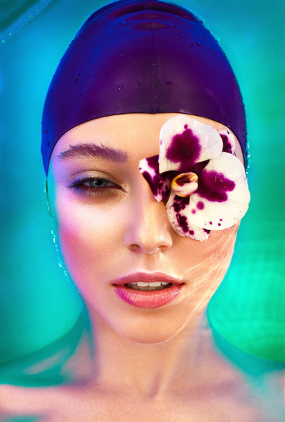 Woman laying in water with orchid on face - 写真・画像