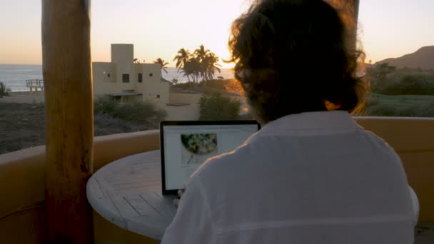 Blogger or graphic designer man working on laptop at home office at beach - Footage, Video