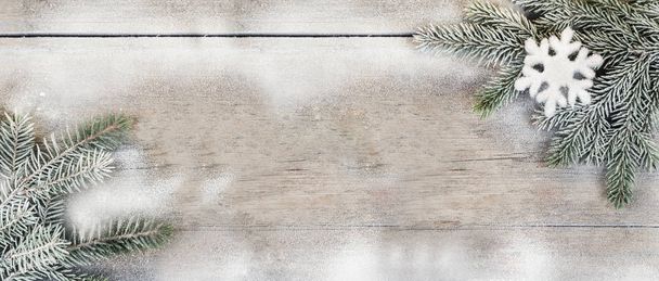 Wooden surface, spruce branch sprinkled with snow and snowflake decoration - Photo, Image