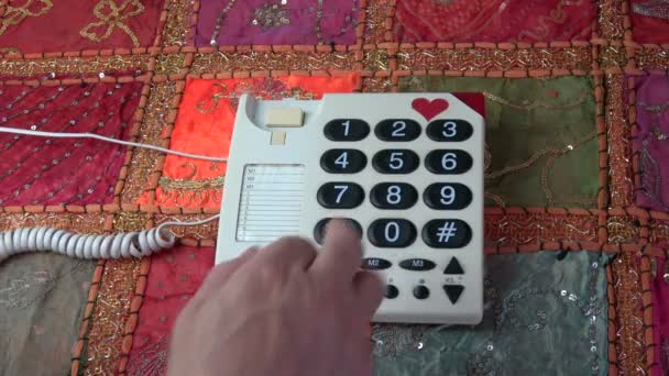 Ο άνθρωπος δάχτυλο πατώντας κουμπιά αριθμών στο κλασικό ρετρό συσκευή τηλεφώνου στο ζωηρόχρωμο τραπεζομάντιλο - Πλάνα, βίντεο