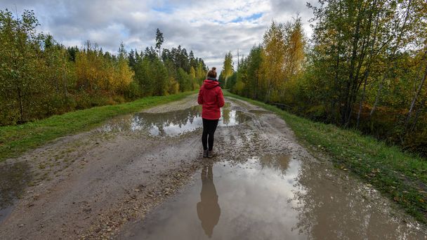 young woman in red jacket enjoying nature on dirt road. Latvia - Foto, imagen