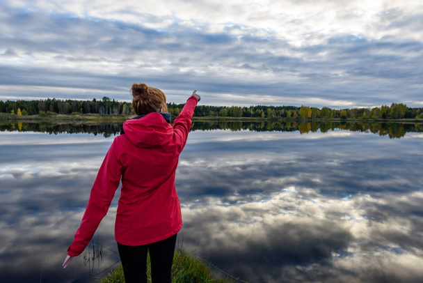 jeune femme en veste rouge profitant de la nature sur le chemin de terre. Lettonie
 - Photo, image