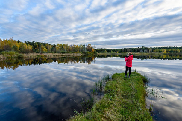 young woman in red jacket enjoying nature on dirt road. Latvia - Fotó, kép