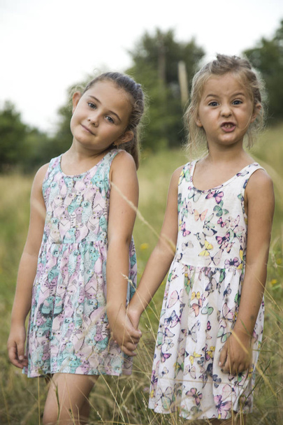 children friend girls playing whispering on flowers grass in vac - Foto, Imagen