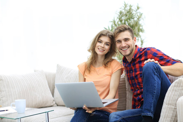 young couple of students with laptop sitting on the couch - Photo, Image