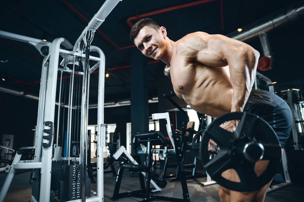 Handsome model young man training back in gym - 写真・画像