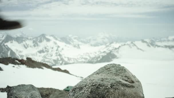 Wanderfüße in Lederschuhen stampfen bei schneebedecktem Bergpanorama auf Felsen - Filmmaterial, Video