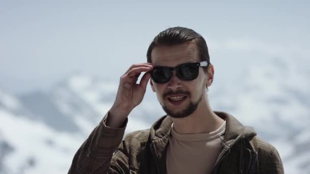 Νέοι γενειοφόρος άνδρας με γυαλιά ηλίου στη σύνοδο κορυφής του βουνού με γραφική άποψη με το επιχείρημα - Πλάνα, βίντεο