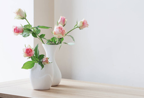 Ροζ τριαντάφυλλα σε βάζο σε λευκό φόντο - Φωτογραφία, εικόνα