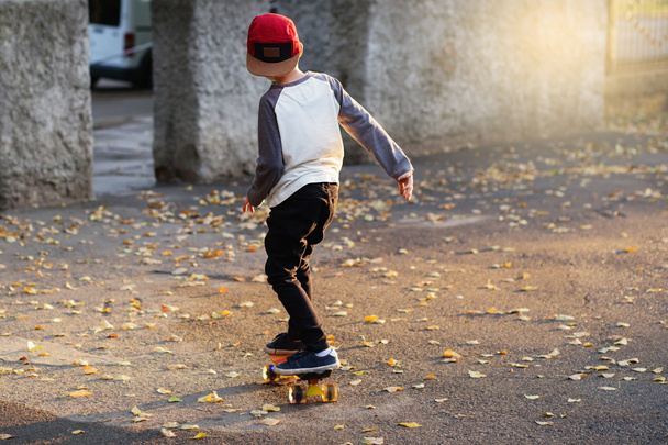 Little urban boy with a penny skateboard. Young kid riding in th - Foto, afbeelding