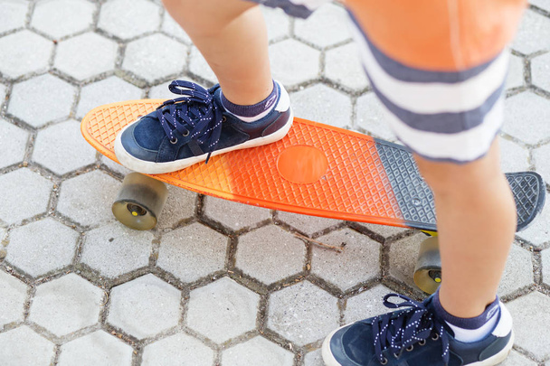 Little urban boy with a penny skateboard. Young kid riding in th - Фото, зображення