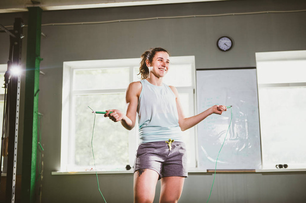 Jovem branca sorrindo mulher segurando uma corda pulando - Conceito de saúde e fitness
 - Foto, Imagem