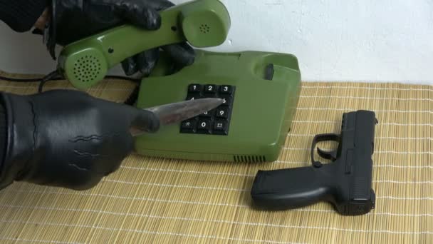Ryöstäjä gangsteri käsi musta käsine ja tikari ase painamalla numeroita painikkeita vanhassa puhelimessa
  - Materiaali, video