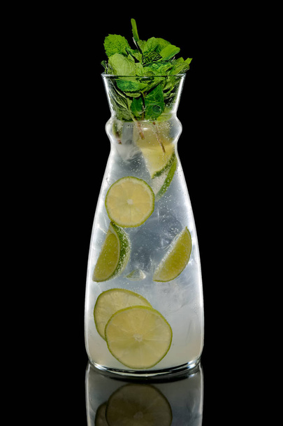 Cold tasty Mojito in pot with reflection on black background - Фото, изображение