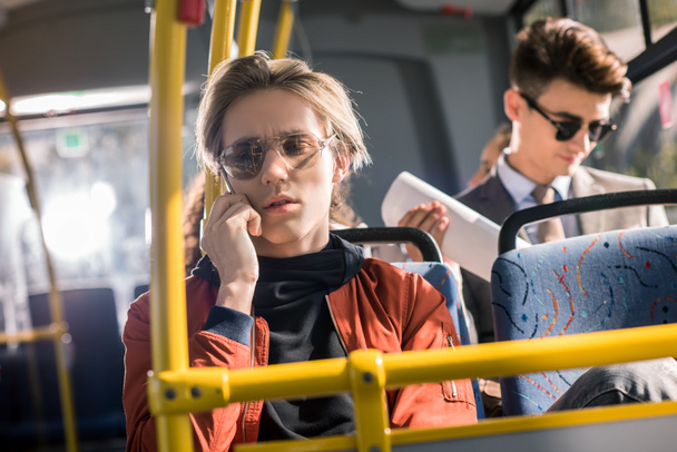 mies käyttää älypuhelinta bussissa
 - Valokuva, kuva