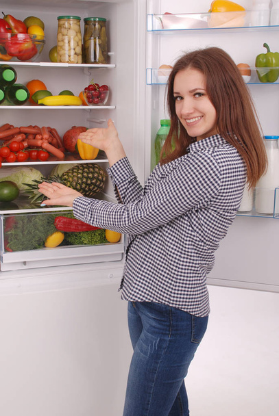 Satisfied housewife near filled fridge. - Foto, Bild