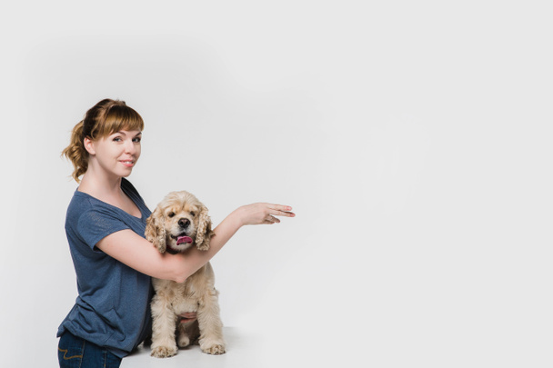 右にある空間を指している犬を持つ女性 - 写真・画像
