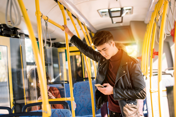 mies käyttää älypuhelinta bussissa
 - Valokuva, kuva