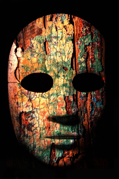 Текстурированная маска с потрескавшейся поверхностью из древесины, нейтральное выражение лица на тёмном фоне
. - Фото, изображение
