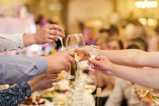 people clinking glasses with each other,Clinking glasses with alcohol and toasting, party,people, leisure and drinks concept - close up of male hands clinking glasses with alcohol and pretzels at bar or pub - Photo, Image