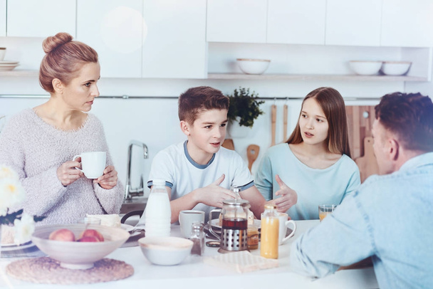 Four membered family chatting during breakfast - Foto, Bild