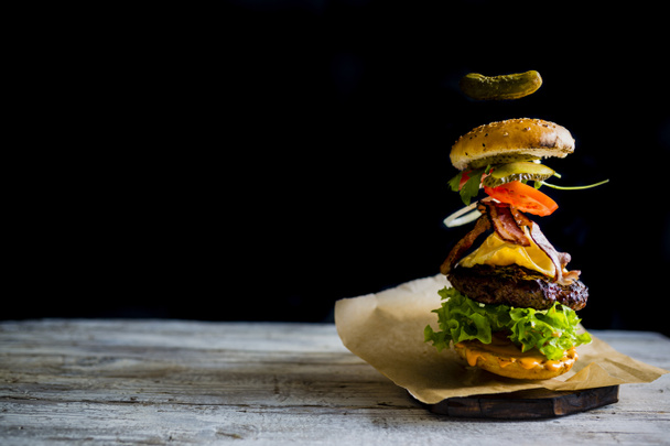 Hamburger avec des ingrédients volants réalistes. Grille fumée savoureuse
 - Photo, image