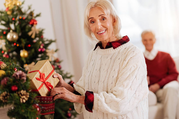 Attractive female person putting present into stocking - Фото, изображение