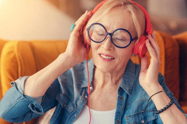 Delighted aged woman listening to music - Фото, зображення