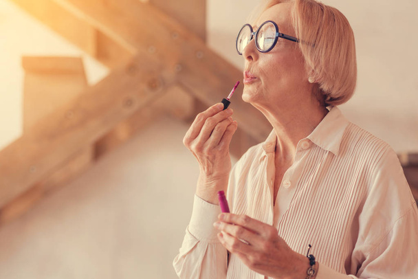 Beautiful aged woman applying lip gloss - Photo, Image