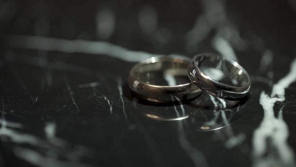 Snubní prsteny na černý mramorový kamenný stůl. Dva kroužky na černý mramorový stůl - Fotografie, Obrázek