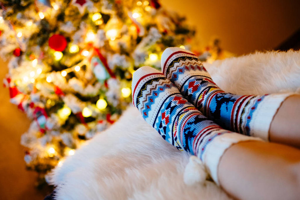 Womans Feet in woollen socks at Christmas tree. - Фото, изображение