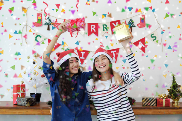 Two beautiful women in Santa hats and holding gift boxes having  - Foto, Imagem