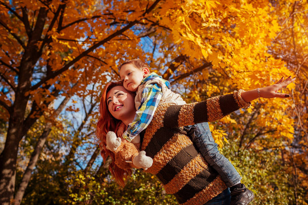 Happy mother and her little son walking and having fun in autumn forest. - Φωτογραφία, εικόνα