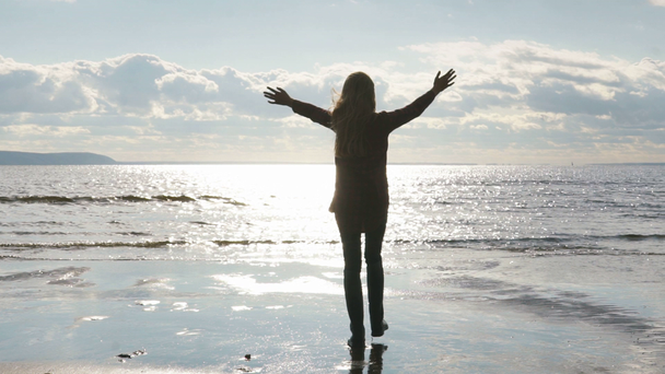 meisje op het strand werpt zijn armen naar de hemel - Video
