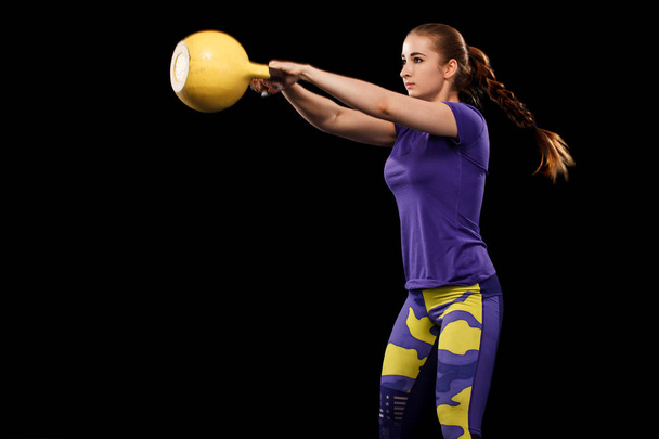 Sporty beautiful woman with dumbbell exercising at black background to stay fit. Crossfit workout motivation. - Foto, Imagen