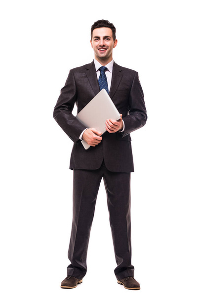 Volledige lengte van aantrekkelijke jonge zakenman wandel- en houdt van laptop over Wit - Foto, afbeelding