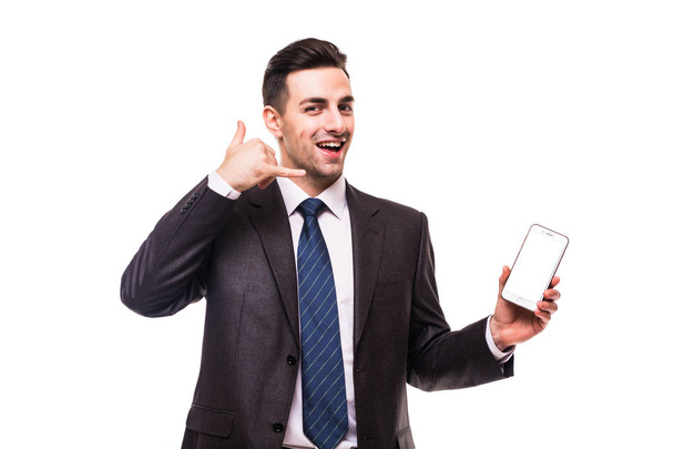 Young attractive man in a blue suit with the phone shows a hand gesture call me on white - Фото, зображення