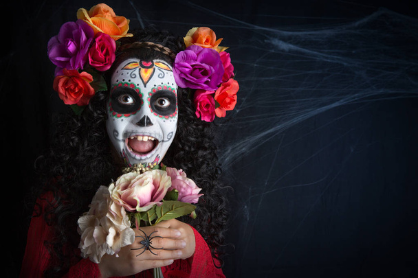 Маленькая девочка с сахарным черепом в костюме девушки на Хэллоуин с белым раскрашенным лицом
 - Фото, изображение
