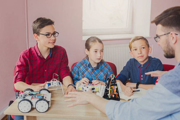 Stem education. Kids creating robots with teacher - Photo, Image