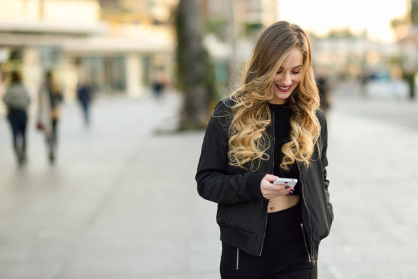 Kobieta blonde SMS-y z jej smartphone w wielkomiejskim - Zdjęcie, obraz