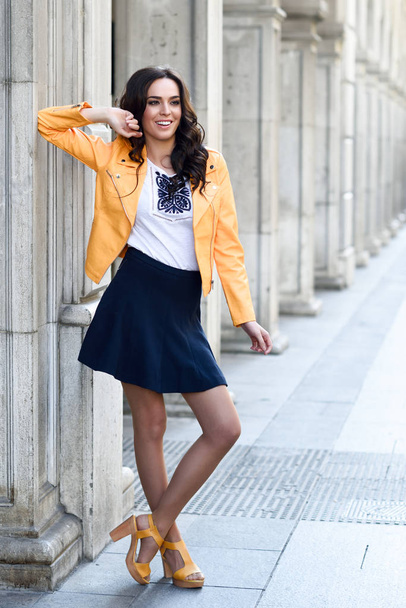 Young brunette woman smiling in urban background. - Фото, изображение