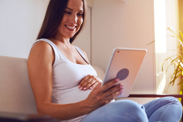 Открытая беременная женщина с помощью цифрового планшета
 - Фото, изображение