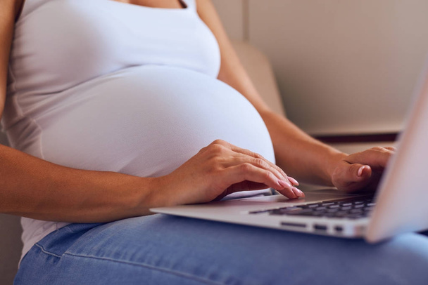 Les mains de la femme enceinte tapant sur ordinateur portable à la maison
  - Photo, image
