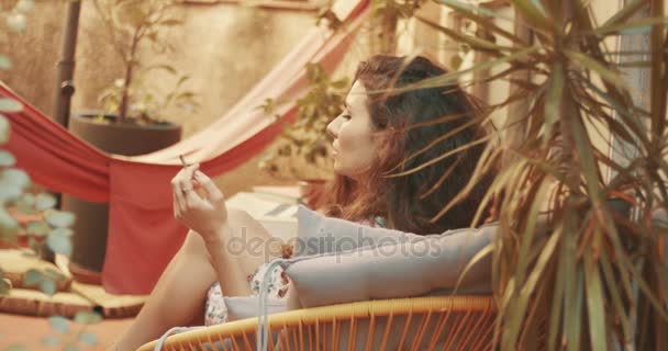 Woman with long curly hair relaxing and smoking - Footage, Video