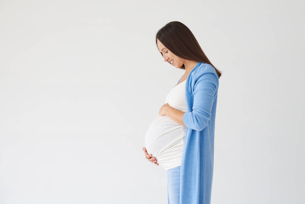 Vista laterale della donna che guarda la pancia incinta
 - Foto, immagini